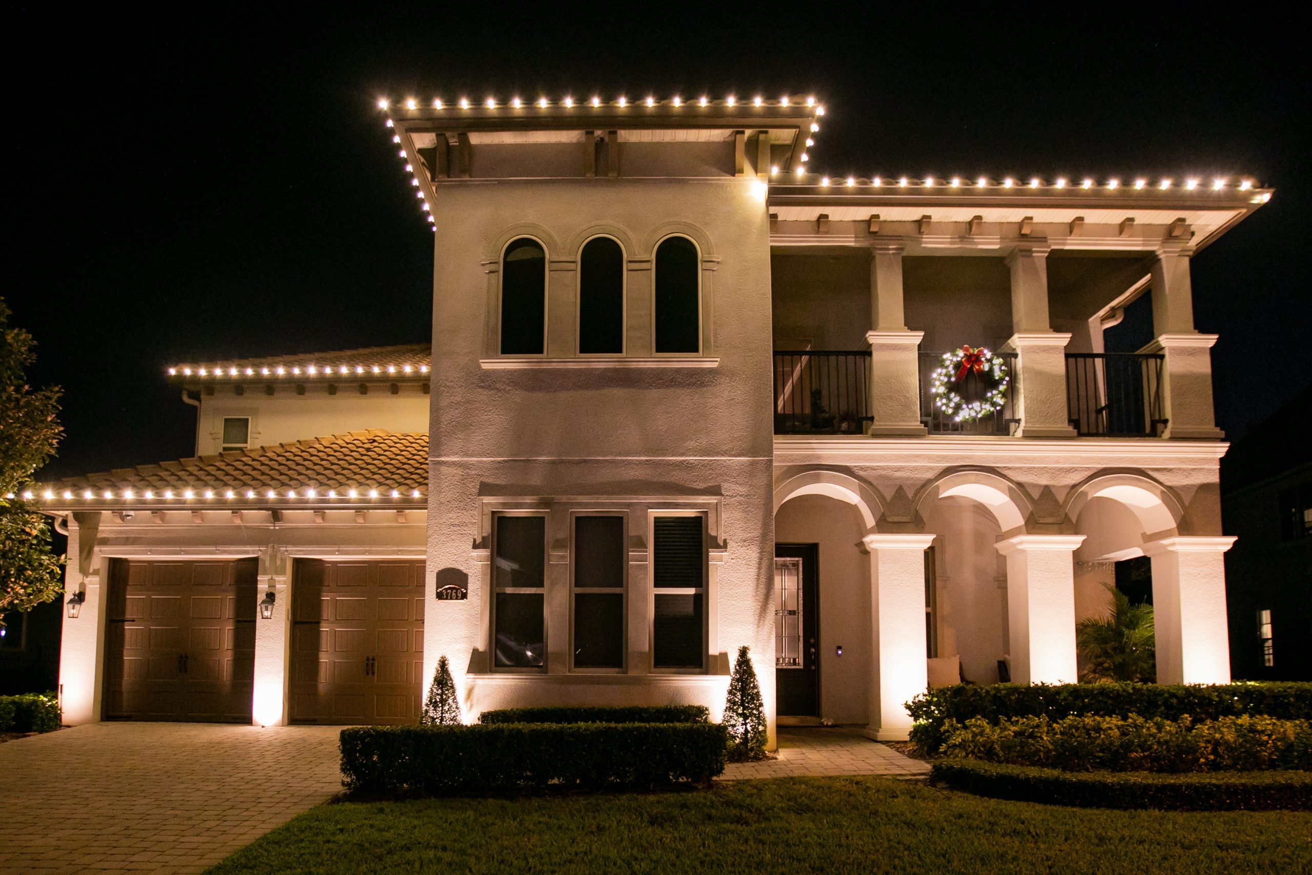 Residential home with roofline lighting and a lit wreath